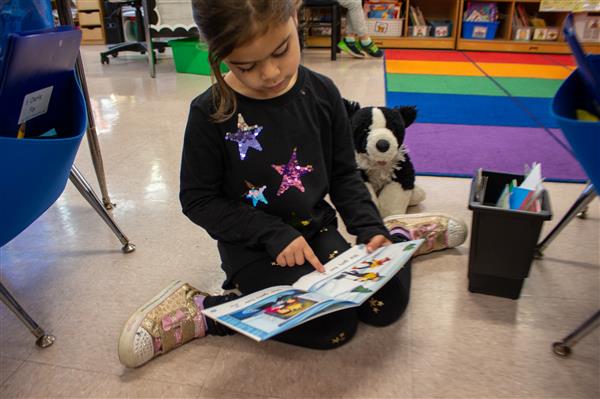 student reading book to stuffed animal